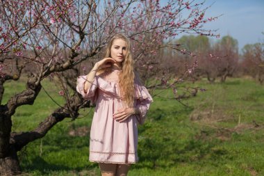 pembe çiçekleri ile baharda çiçekli Şeftali Bahçesi güzel sarışın kadın