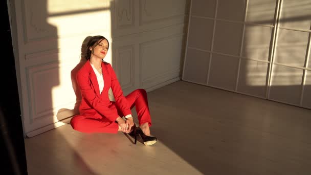 Vonzó Brunette piros öltönyt ül stúdió — Stock videók