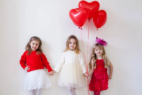 Три маленькі красиві дівчата в червоному тримають руки — стокове фото