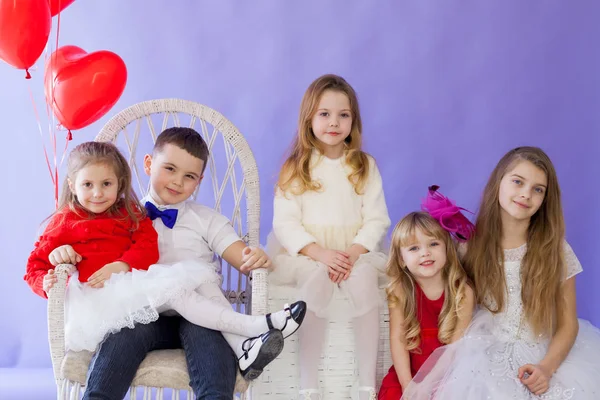 Pojke och flickor sitter tillsammans med röda ballonger — Stockfoto
