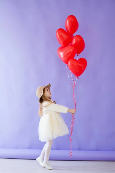 Bella ragazza siede con palloncini cuore rosso — Foto Stock