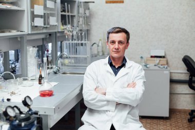 Araştırmacı test tüplerini kontrol ediyor. Adam koruyucu gözlük ve maske giyer