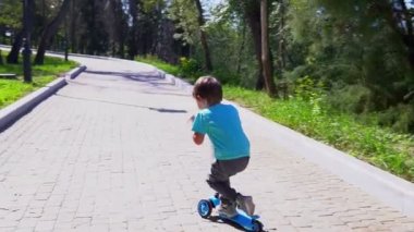 Küçük çocuk scooter'a biniyor.