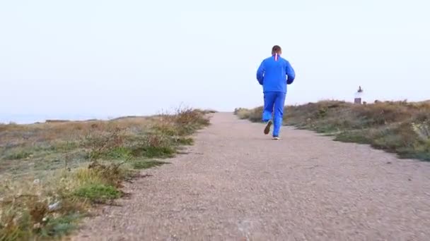 Young athletic man doing gymnastics on the sea early in the morning — Stock Video