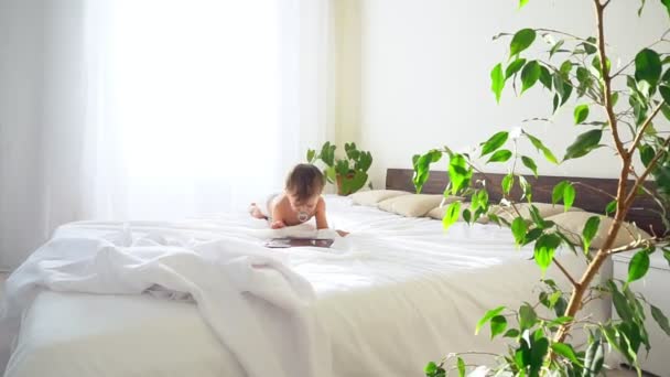 Little boy looks into tablet lying in bed — Stock Video