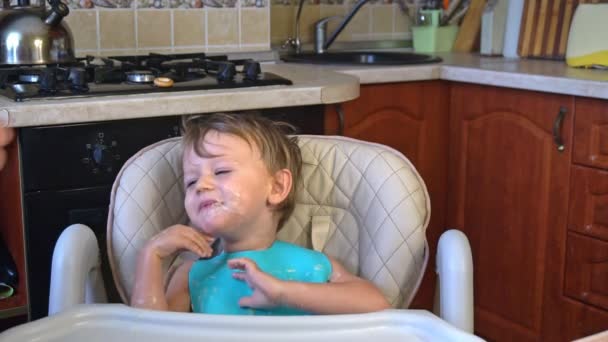 Тато годує маленьких хлопчиків кашею на кухні — стокове відео