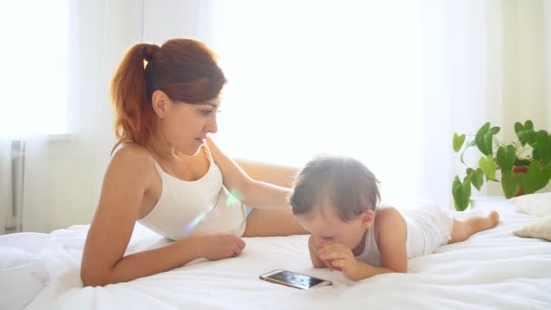 Mamma och son tittar på smartphone i sovrummet — Stockvideo