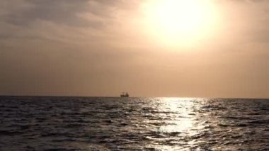 Deniz giden gemiler, tankerler siluetleri ile Altın günbatımı