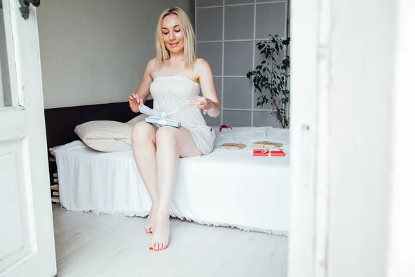 Vrouw blonde opent cadeau in de ochtend in de slaapkamer — Stockfoto