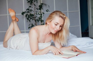 Kadın sarışın yatakta yatak odasında bir kitap okur