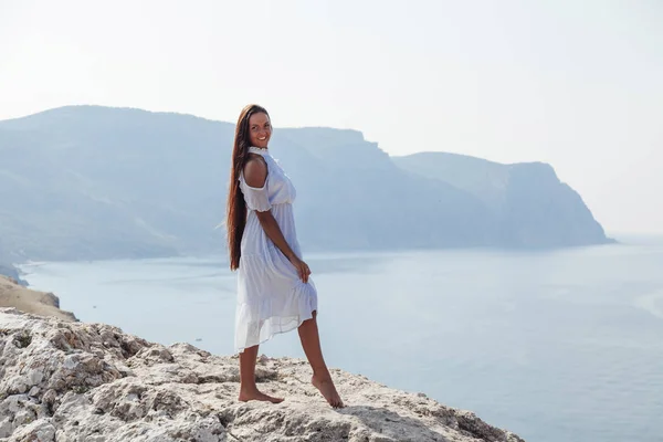 Beautiful woman with long hair on a cliff ocean — Stock Photo, Image