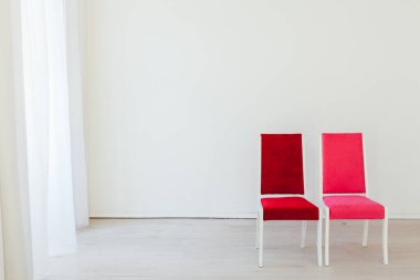 Beyaz odada kırmızı ve pembe iki sandalye.