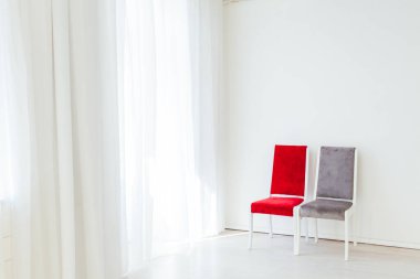 İki sandalye boş beyaz bir odada duruyor.