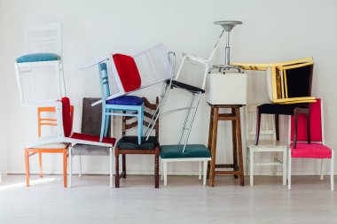 Beyaz odada bir sürü farklı sandalye var.