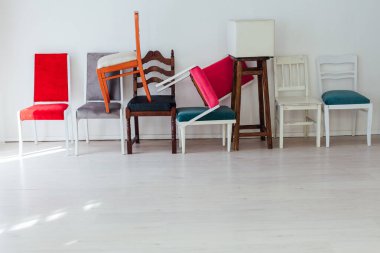 Birçok renkli sandalye beyaz odada duruyor.