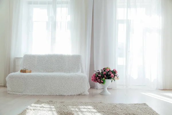 Bílá pohovka s květinami stojí sama v bílém pokoji — Stock fotografie