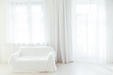 Pencereleri olan beyaz bir odanın içindeki kanepe.