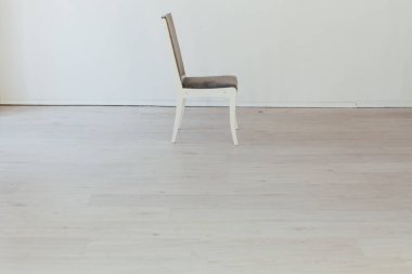 Gri sandalye beyaz odada tek başına duruyor.