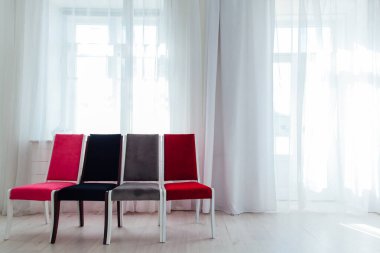 Boş beyaz bir odada dört sandalye duruyor.