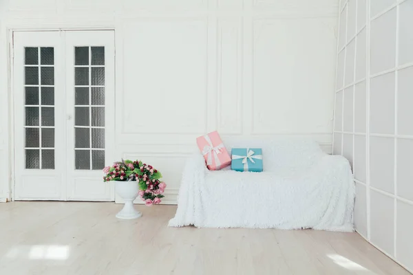 Sofá no interior da sala branca com presentes azuis e rosa para a surpresa — Fotografia de Stock