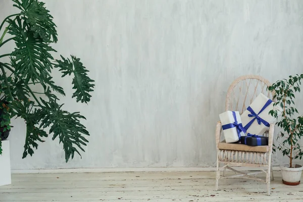 Chaise blanche avec des plantes et des cadeaux dans la chambre grise — Photo