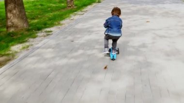 Küçük çocuk scooter'a biniyor.