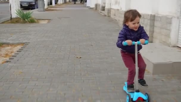 Kind paardrijden scooter op groene kick board. — Stockvideo