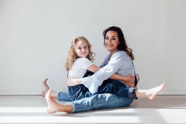 Moeder en dochter in jeans zitten samen knuffelen — Stockfoto
