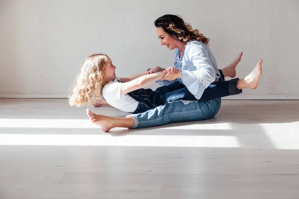 Mom and daughter in jeans sit together cuddling