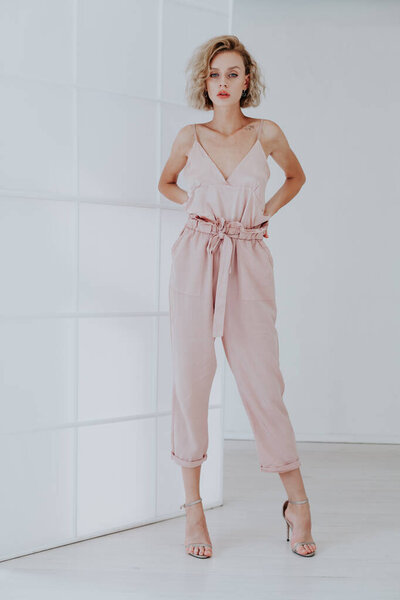 Модный портрет красивой женщины в розовой одежде на белом фоне
