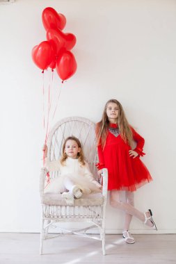 Two little girls with red balloons on Valentines Day