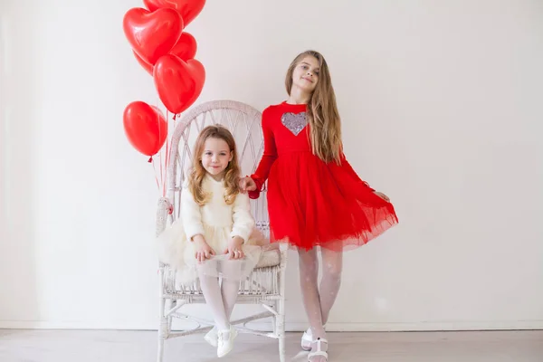 Two little girls with red balloons on Valentines Day — стокове фото