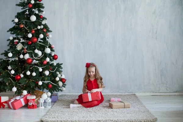 Маленькая девочка украшает новогодние елки подарки — стоковое фото