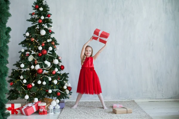 Mała dziewczynka dekoruje choinkę prezenty nowy rok — Zdjęcie stockowe