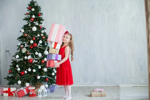 Mała dziewczynka dekoruje choinkę prezenty nowy rok — Zdjęcie stockowe