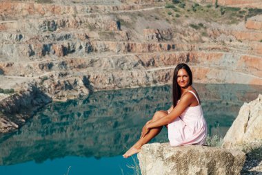 Uzun saçlı bir kadın gölün kıyısındaki bir dağda duruyor.