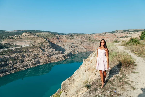 A woman with long hair stands on a mountain by a lake — Stock Photo, Image