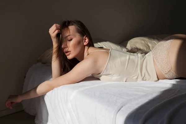 Bela mulher em roupa interior leve no quarto na cama — Fotografia de Stock