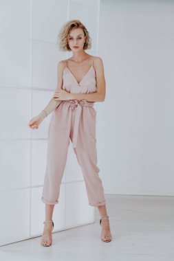 Pembe pantolonlu şık, sarışın bir kadının portresi.