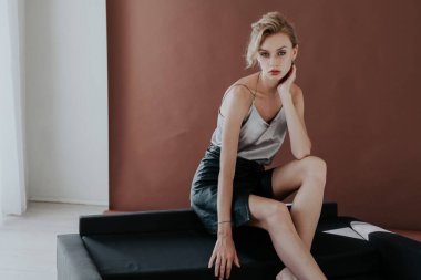 Ofisteki siyah koltukta güzel bir moda işi sarışın kadın.