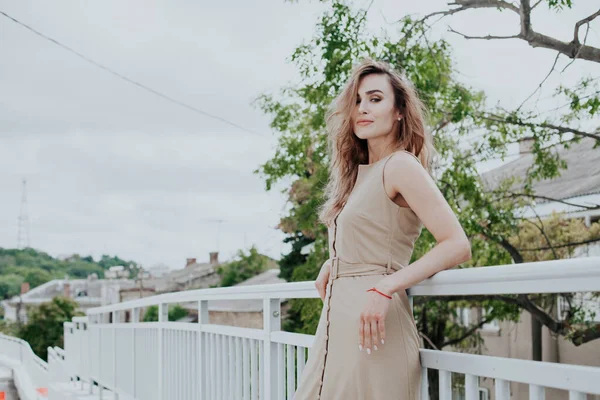 Mooie modieuze vrouw in een beige jurk in het park op een wandeling — Stockfoto