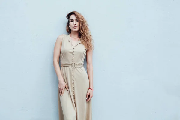 Retrato de una mujer de moda en un vestido beige sobre un fondo gris —  Fotos de Stock