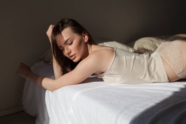 Çarşaflı güzel kadın yatak odasında, yatağın üstünde.