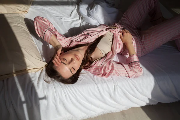 Mooie vrouw in pyjama in de slaapkamer op het bed — Stockfoto