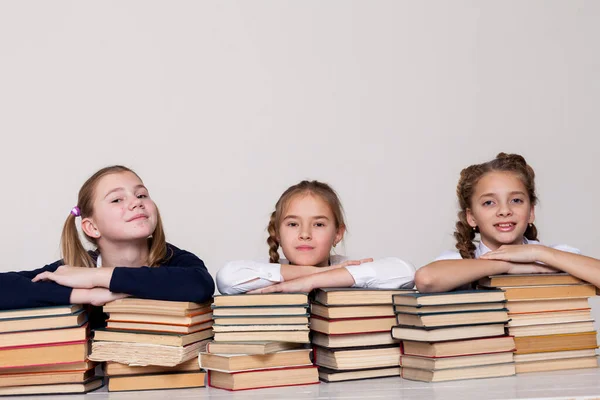 Három lány könyvekkel az osztályban egy íróasztalnál az iskolában — Stock Fotó