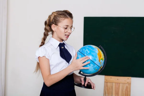 Menina com um globo em aula de geografia no conselho na escola — Fotografia de Stock