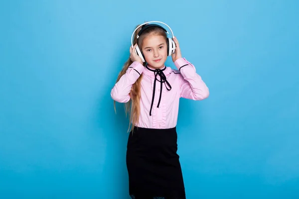Krásná školačka dívka poslouchá hudbu ve velkých sluchátkách — Stock fotografie