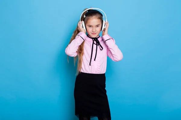 Hermosa colegiala escucha música en los auriculares grandes —  Fotos de Stock