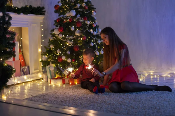 Мама и сын в канун Нового года на елке подарки гирлянды огни — стоковое фото