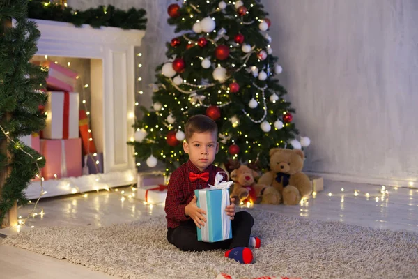 Маленький мальчик в канун Нового года на елке подарки гирлянды огни — стоковое фото